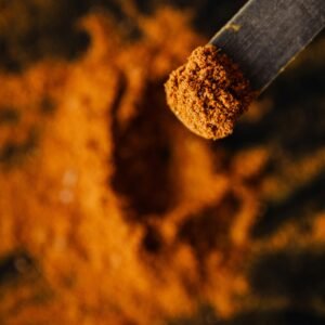 From above dark wooden spatula with sample of ground curcuma taken from heap